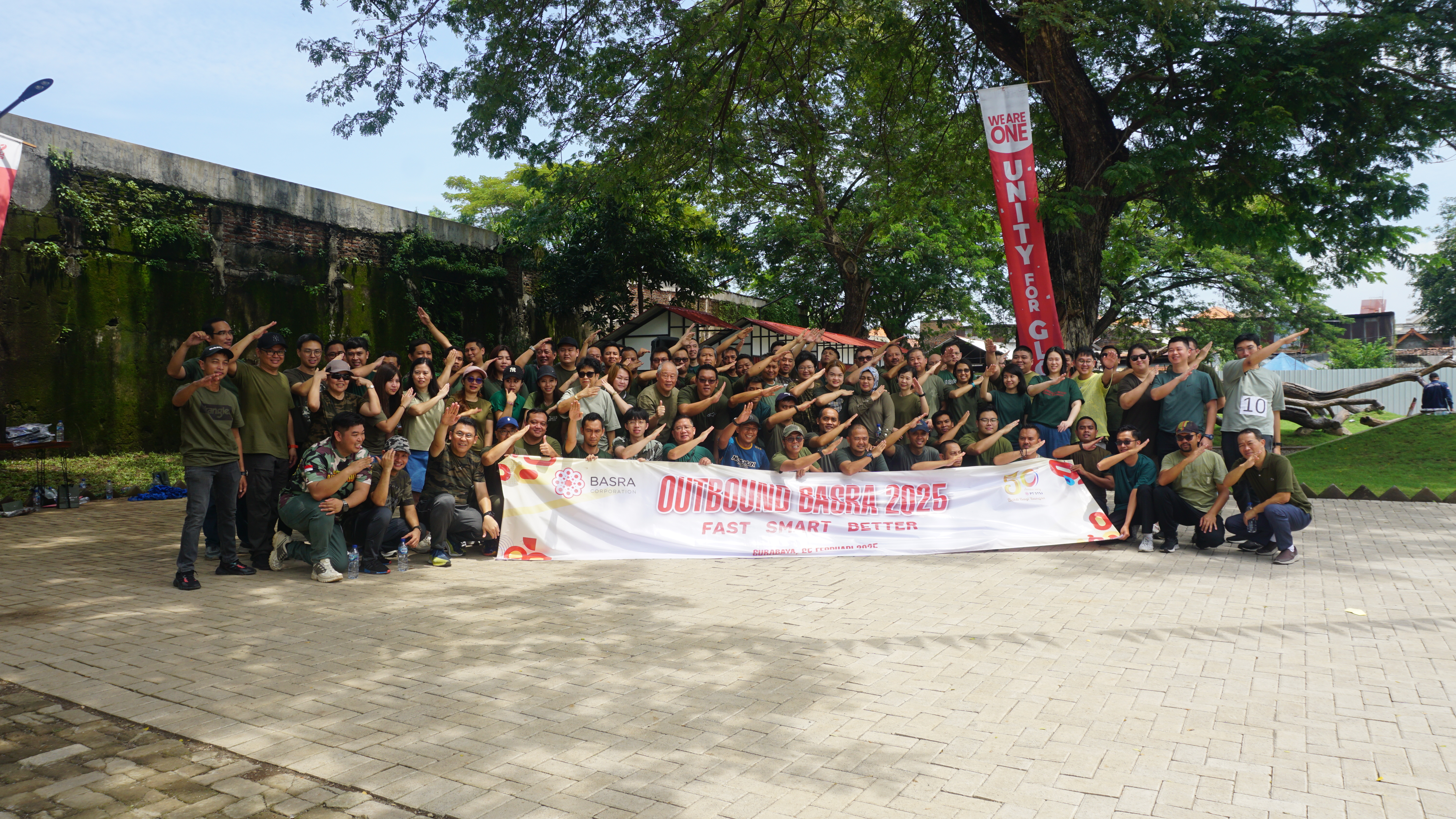 A corporate outbound group gathered for a photo on the paved forecourt at Dupak 36.