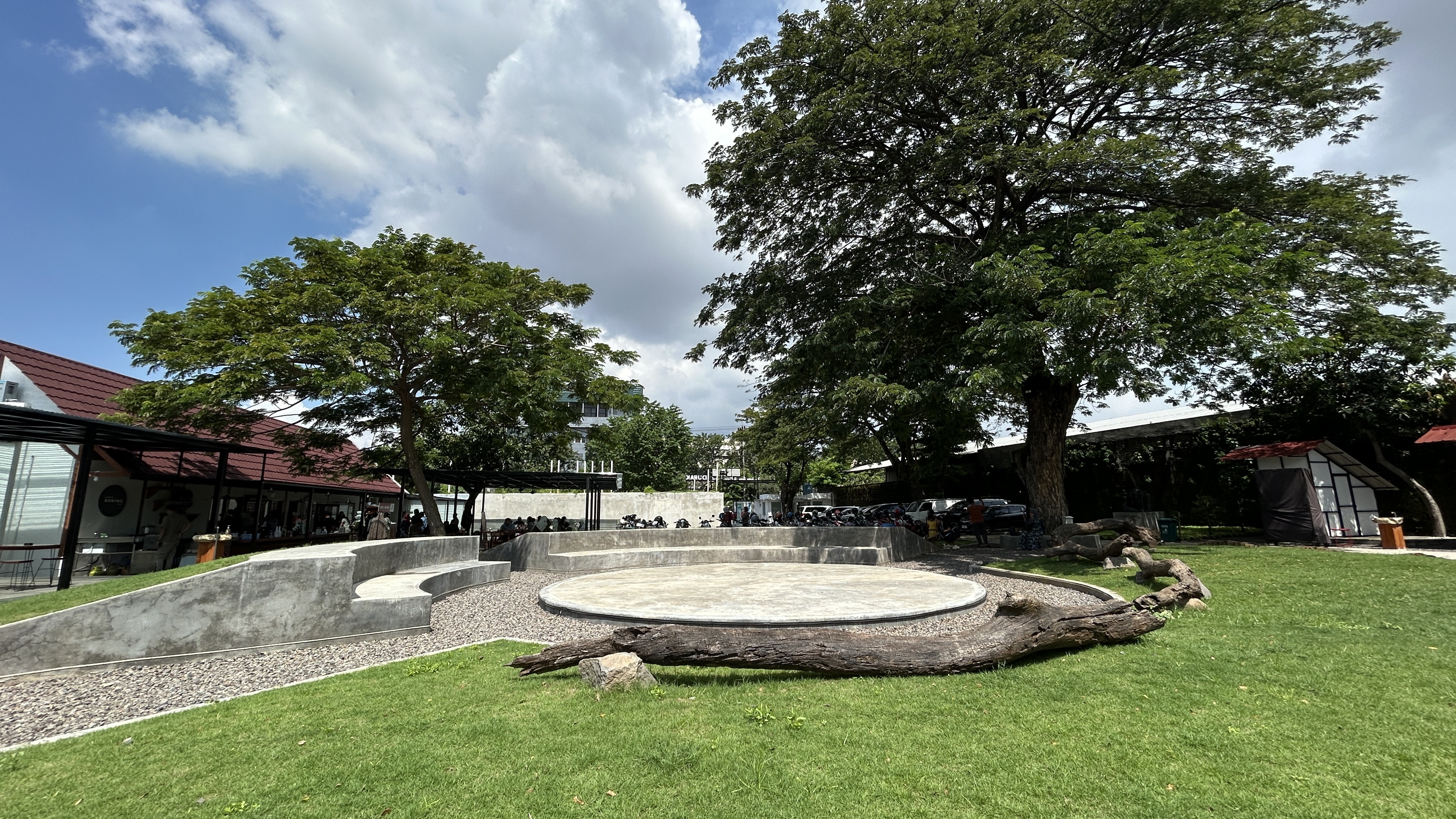 The mini amphitheatre at Dupak 36 — a round concrete stage with tiered seating, backed by tenant units and shaded lawn.